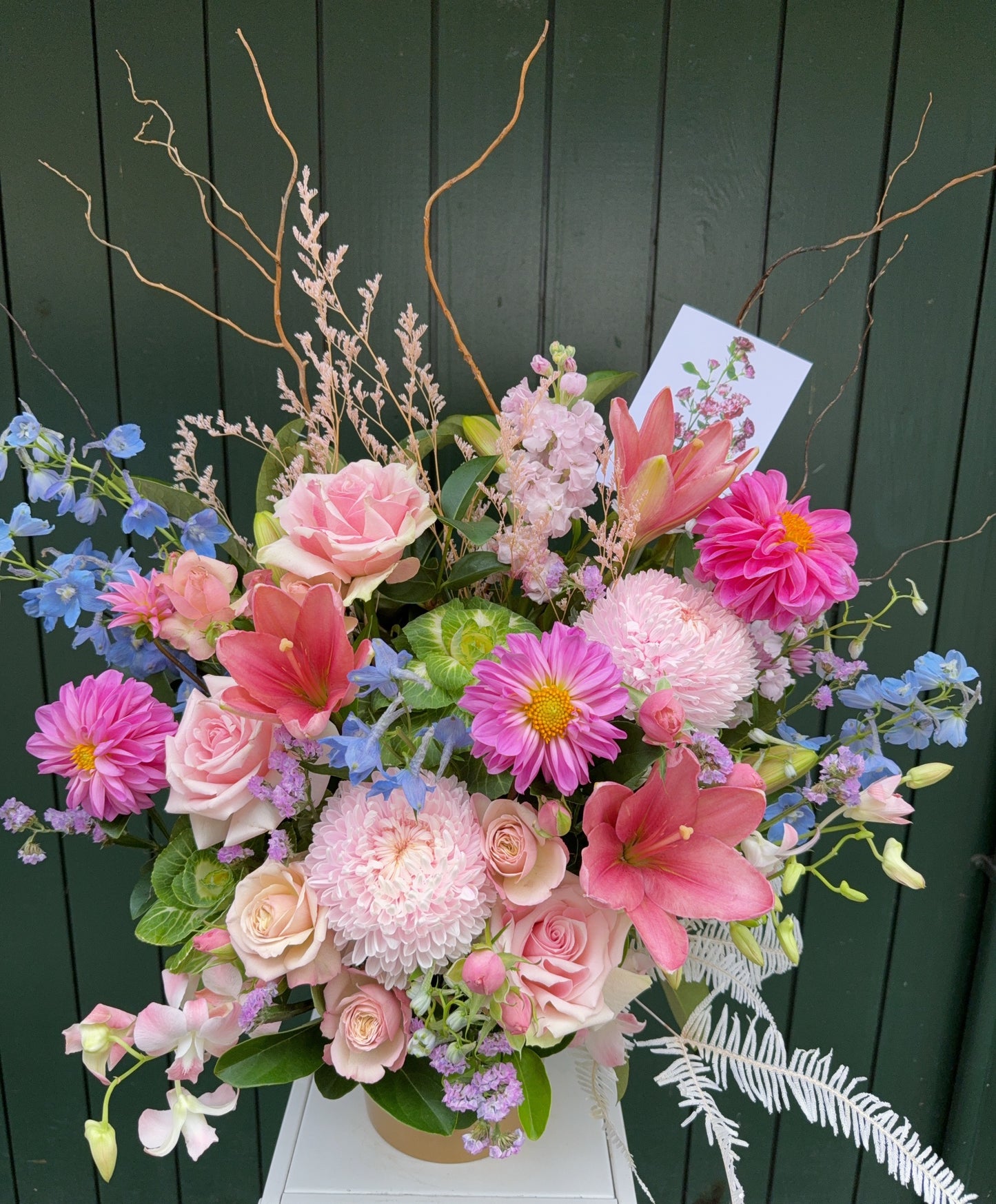 Bright flower arrangement with seasonal pink and blue flowers beautifully arranged in a container.